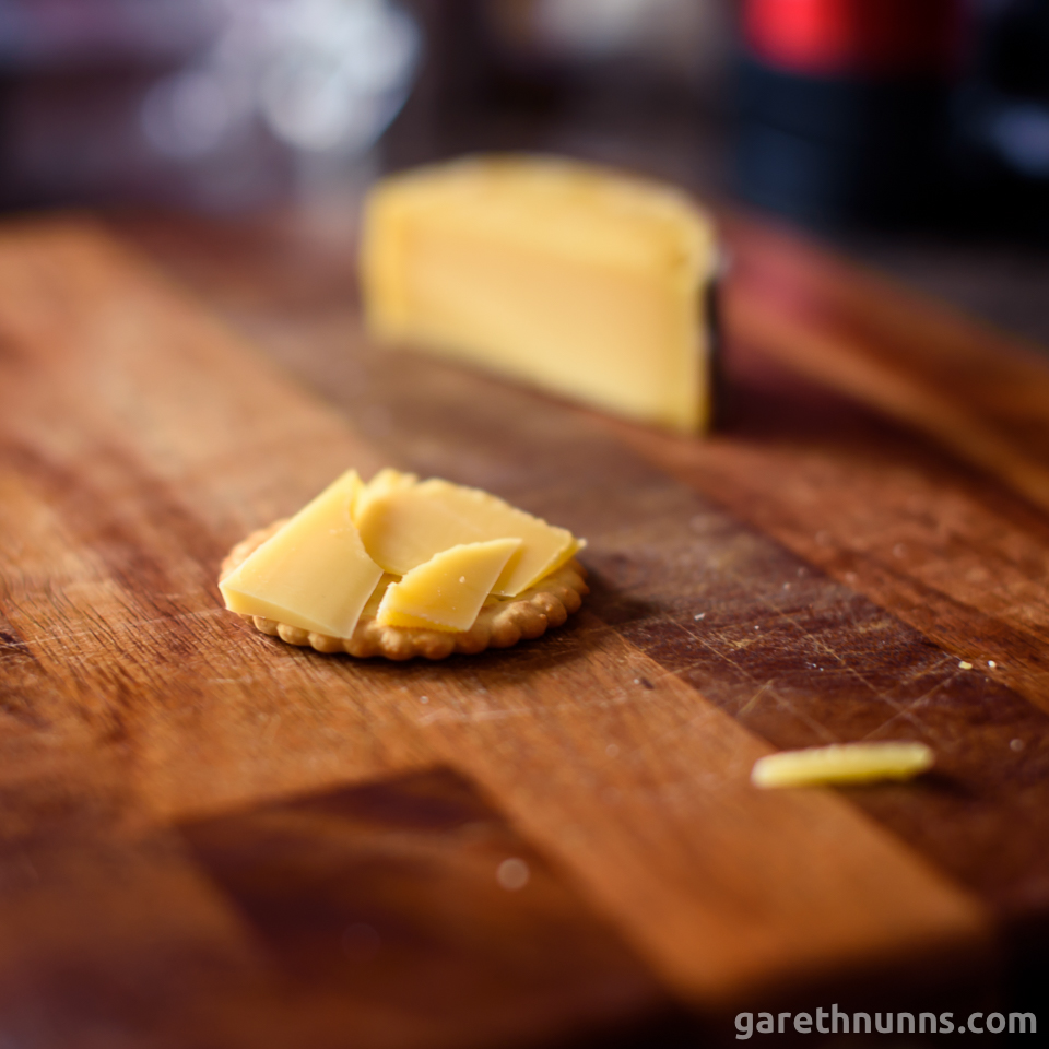 Cheese on cracker on chopping board